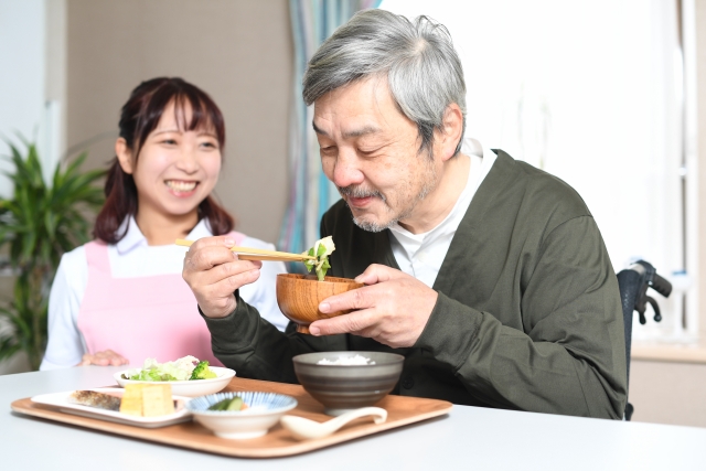 食事をする高齢者男性とエプロン姿の女性介護士