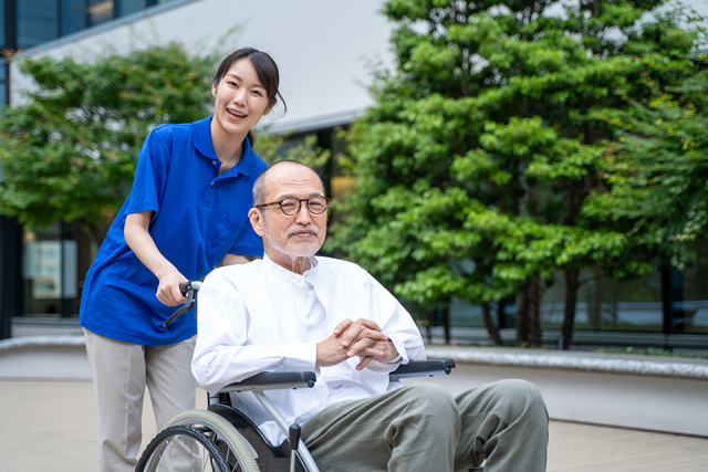 車いすのシニア男性と介護施設スタッフ